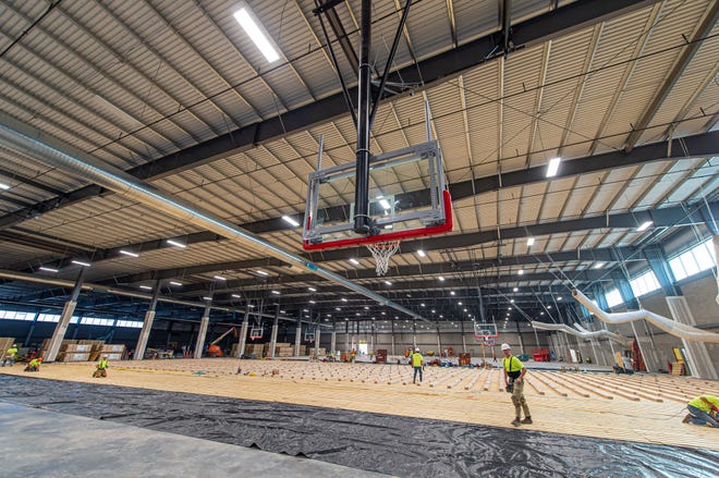 Workers install flooring at one of the basketball courts at Bell Bank Park.